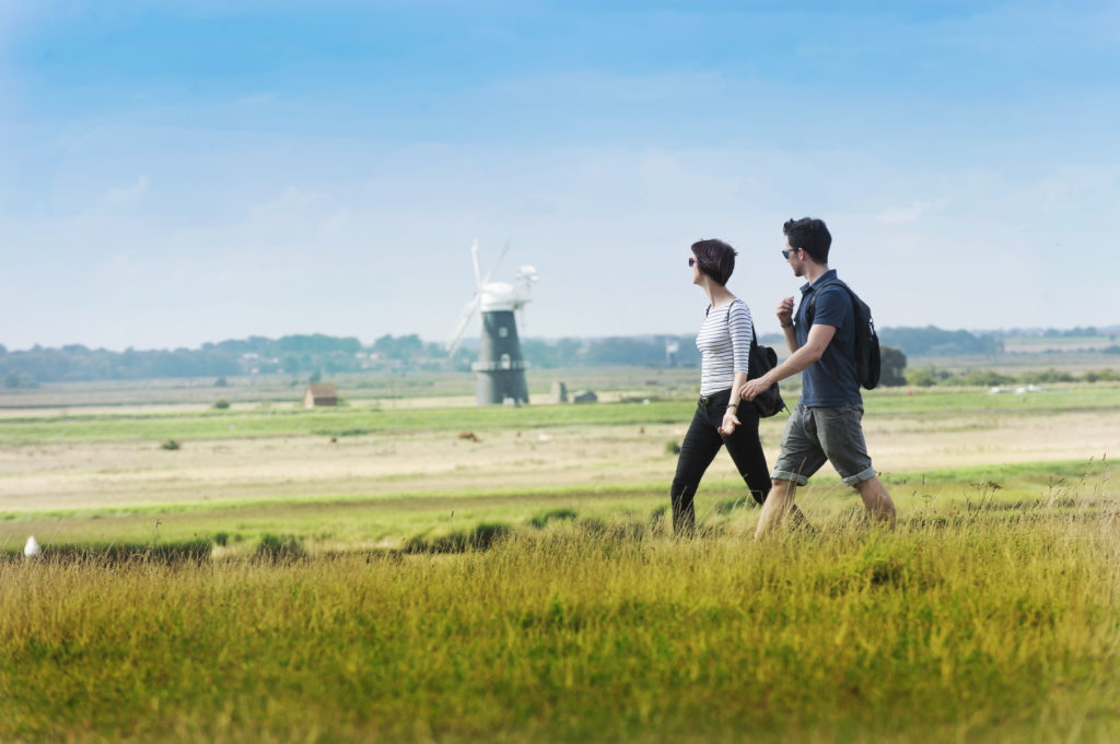 A couple walking through a field with a windmill