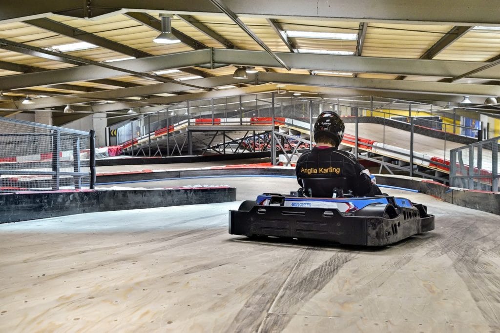 person in a black helmet driving a kart on an indoor track